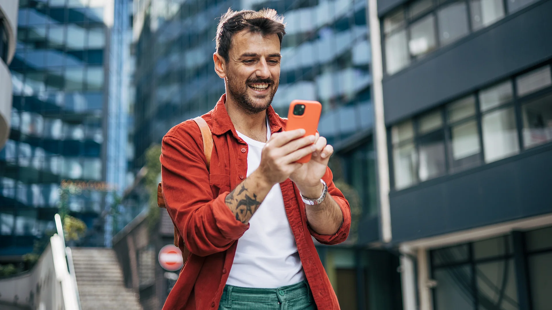Person on a street looking at a smartphone, smiling
