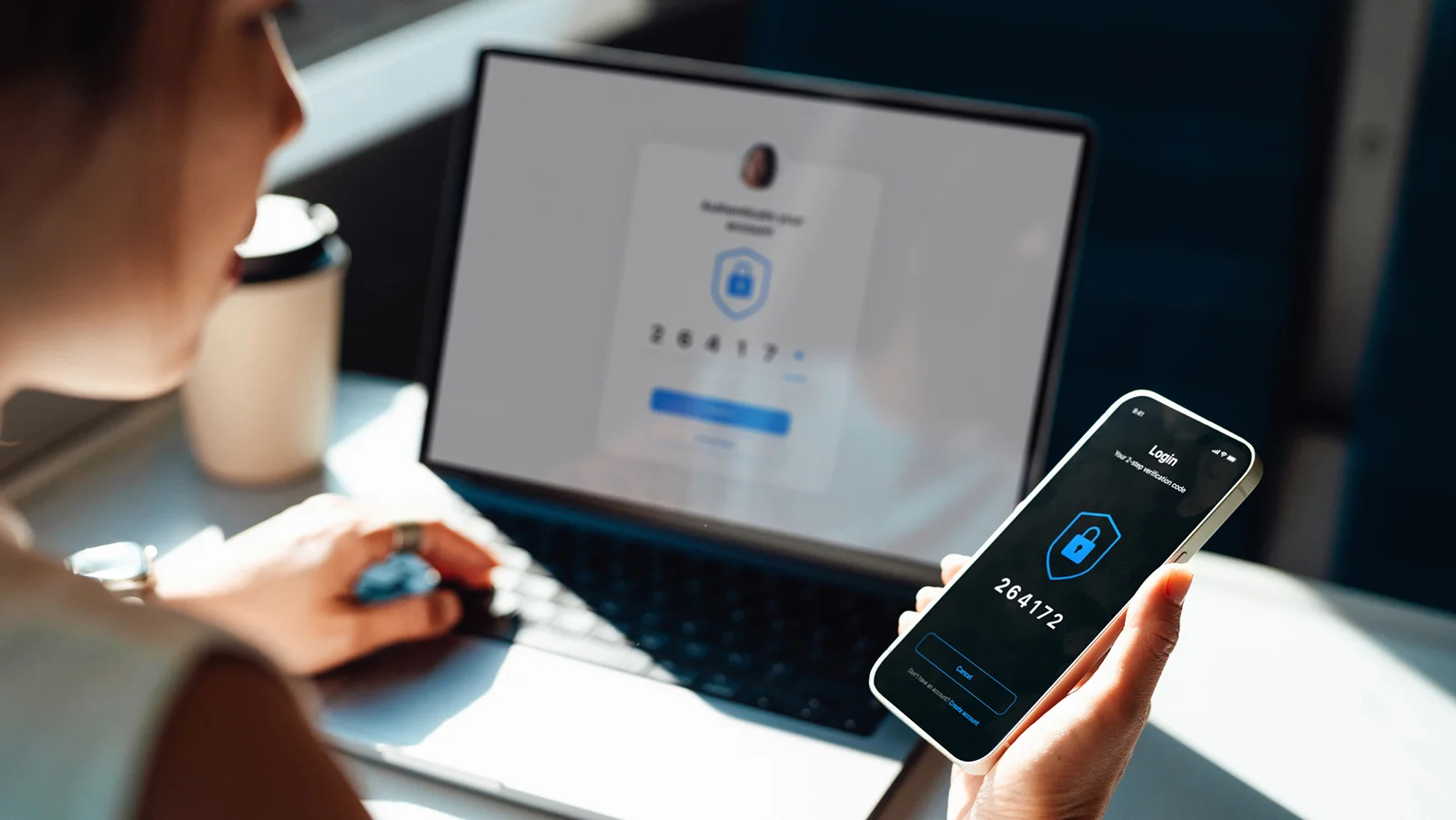Person looking at a smartphone with a password while typing on a computer with the other hand