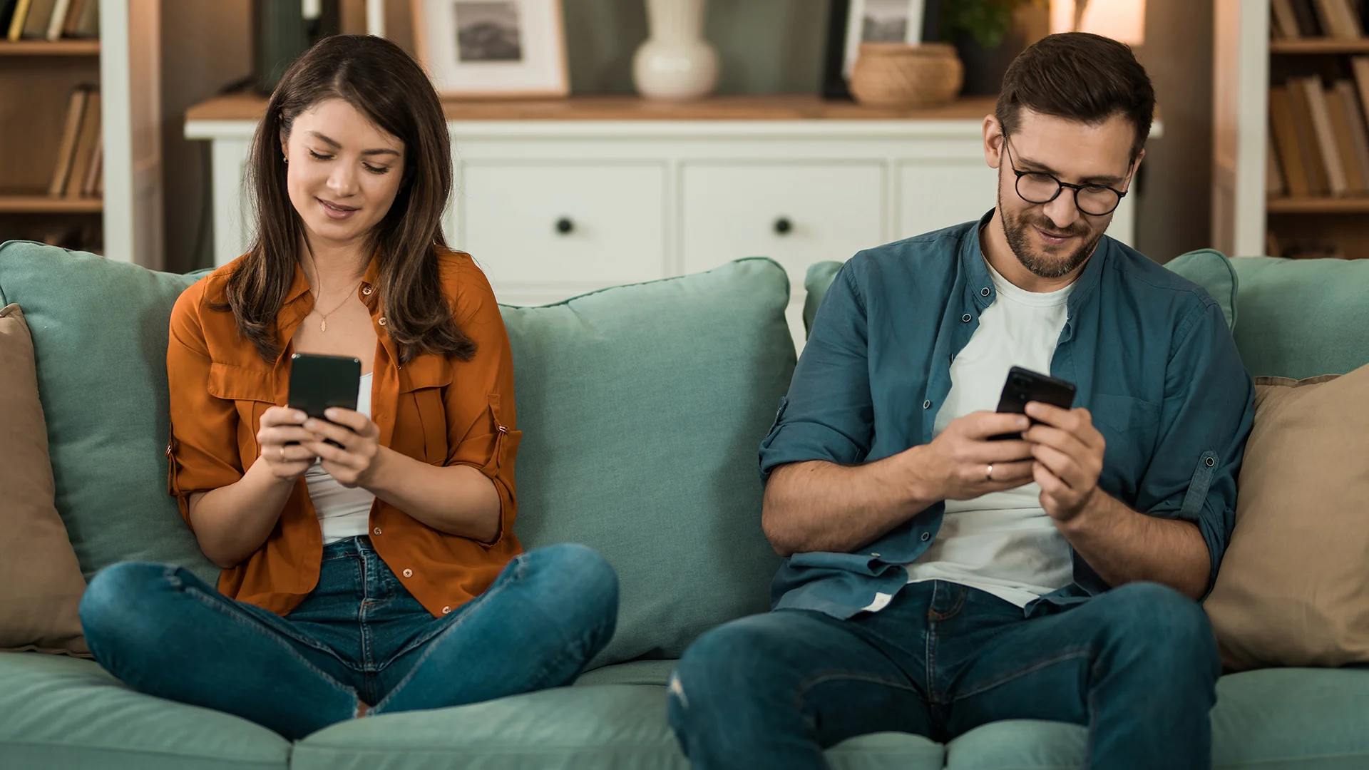 Women and man on their phone while sitting on a sofa in a nicely decorated room