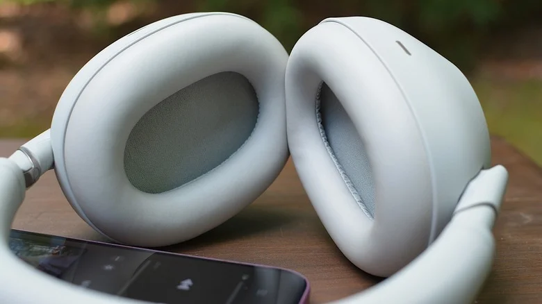 Closeup of the Sony WH-1000XM6 headphones on a table next to a phone.