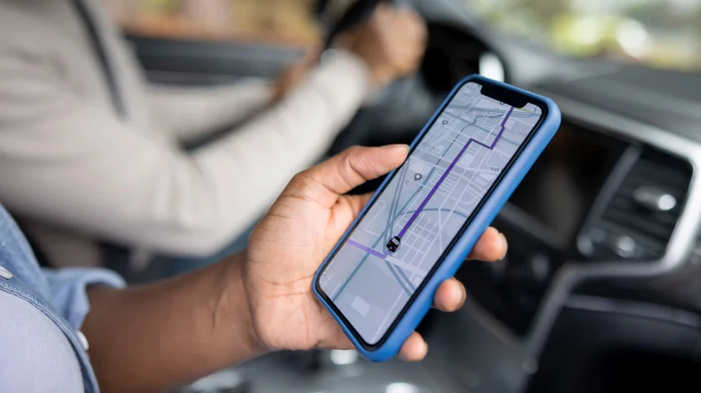 Person using navigation app on iPhone as passenger in car