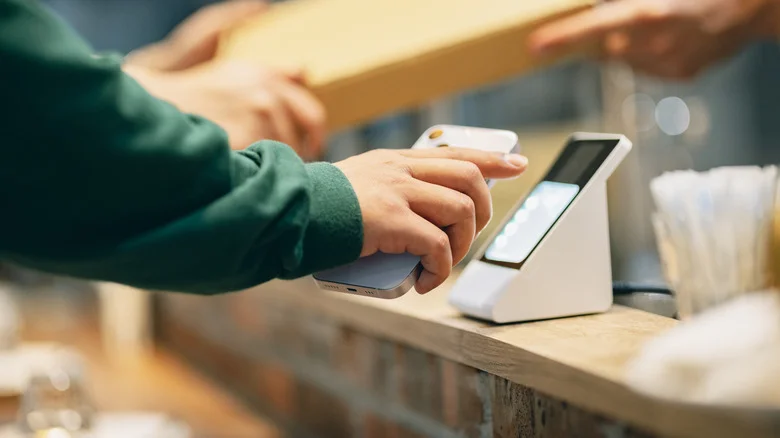 Person tapping their phone to pay in a store.