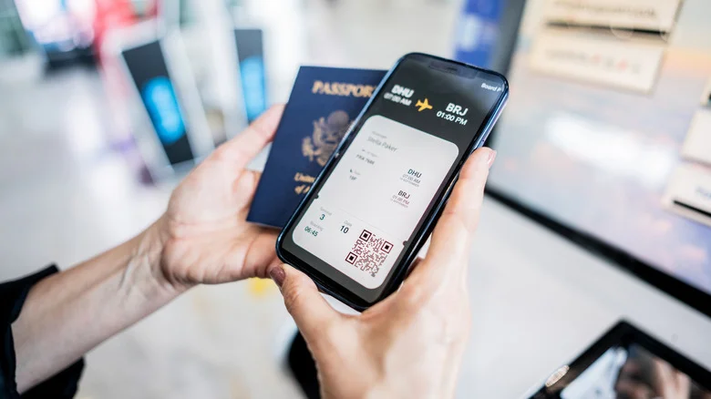 Hands holding a passport and digital airline ticket on a phone.