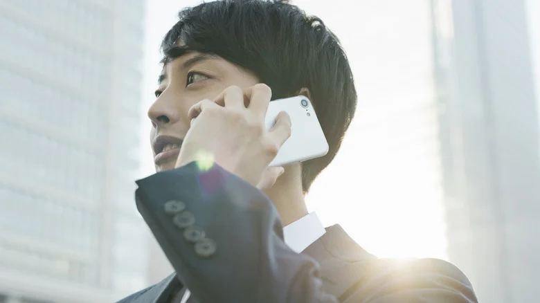 Man taking a phone call on a white Android phone.