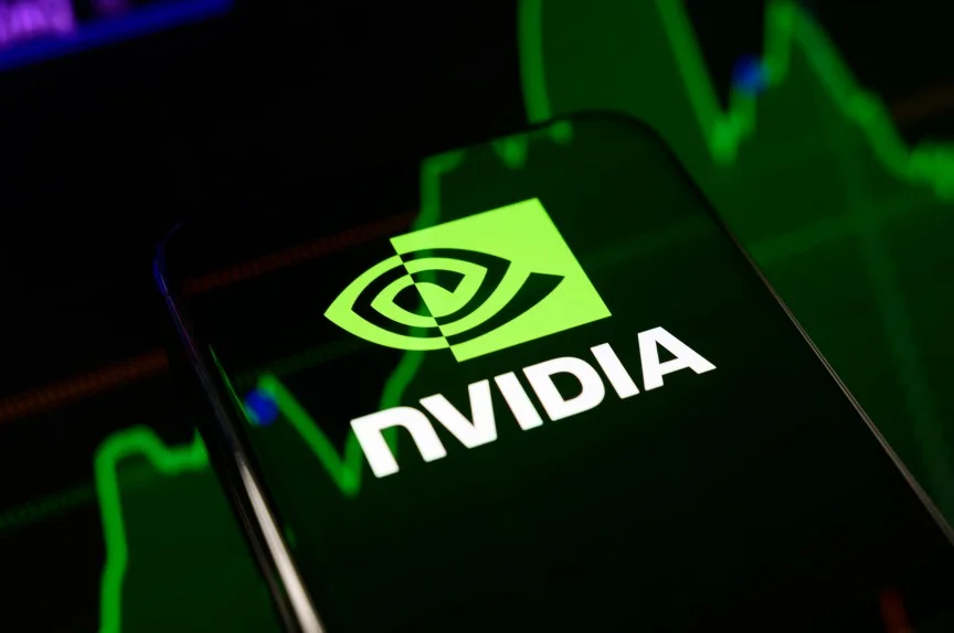 The Nvidia logo displayed on a smartphone screen placed on a reflective surface onto which a stock chart is projected